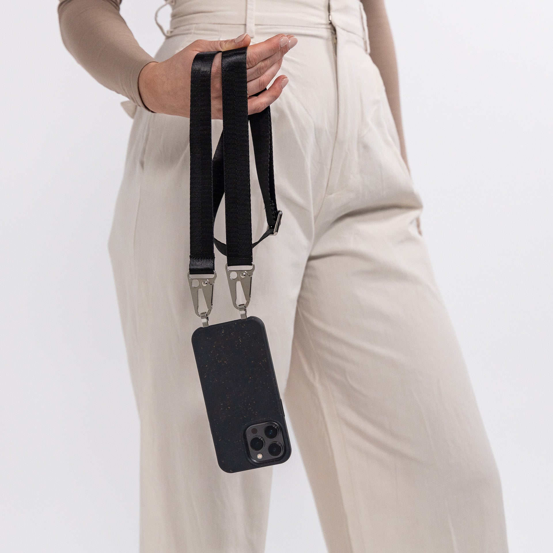 Ink crossbody phone case with black strap hanging off hand from the back
