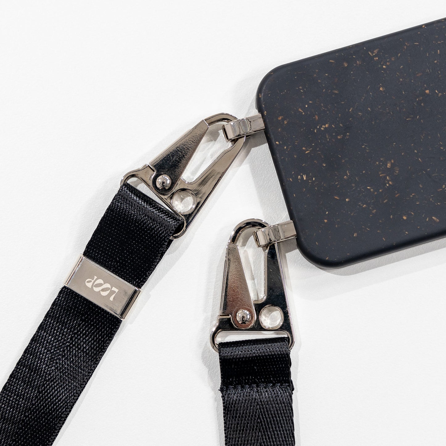 Ink crossbody phone case with black strap close up laying face down