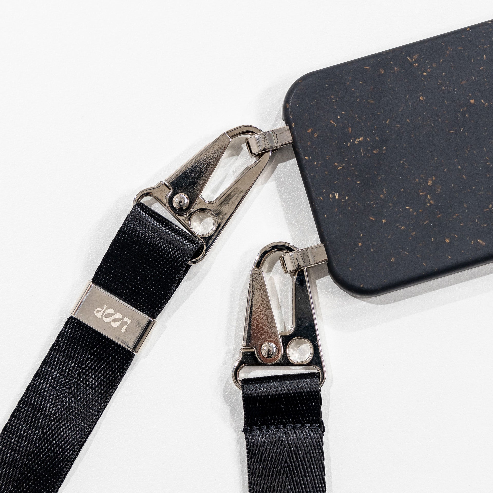 Ink crossbody phone case with black strap close up laying face down