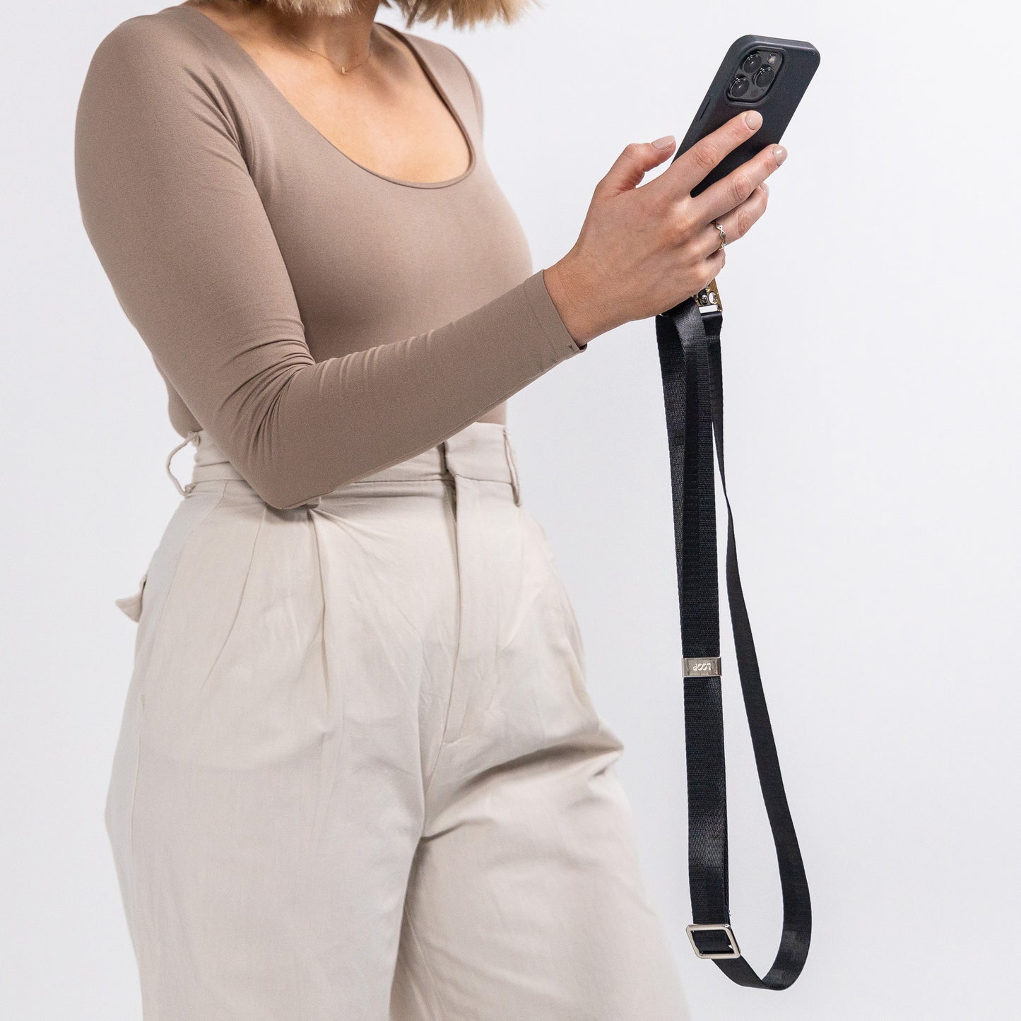 Ink crossbody phone case with black crossbody strap being held in front of body 