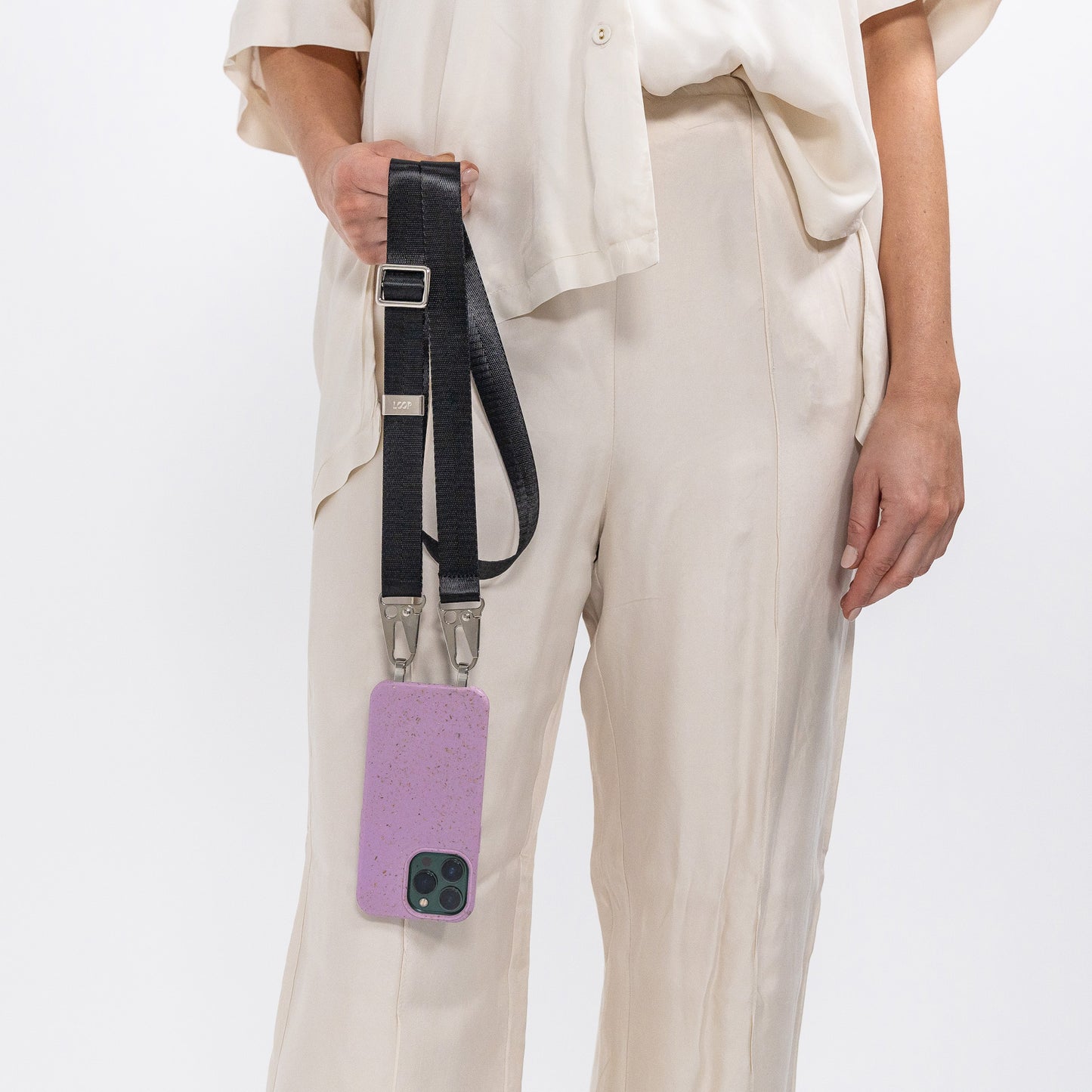 Lavender crossbody phone case with black strap attached being held in front of body 