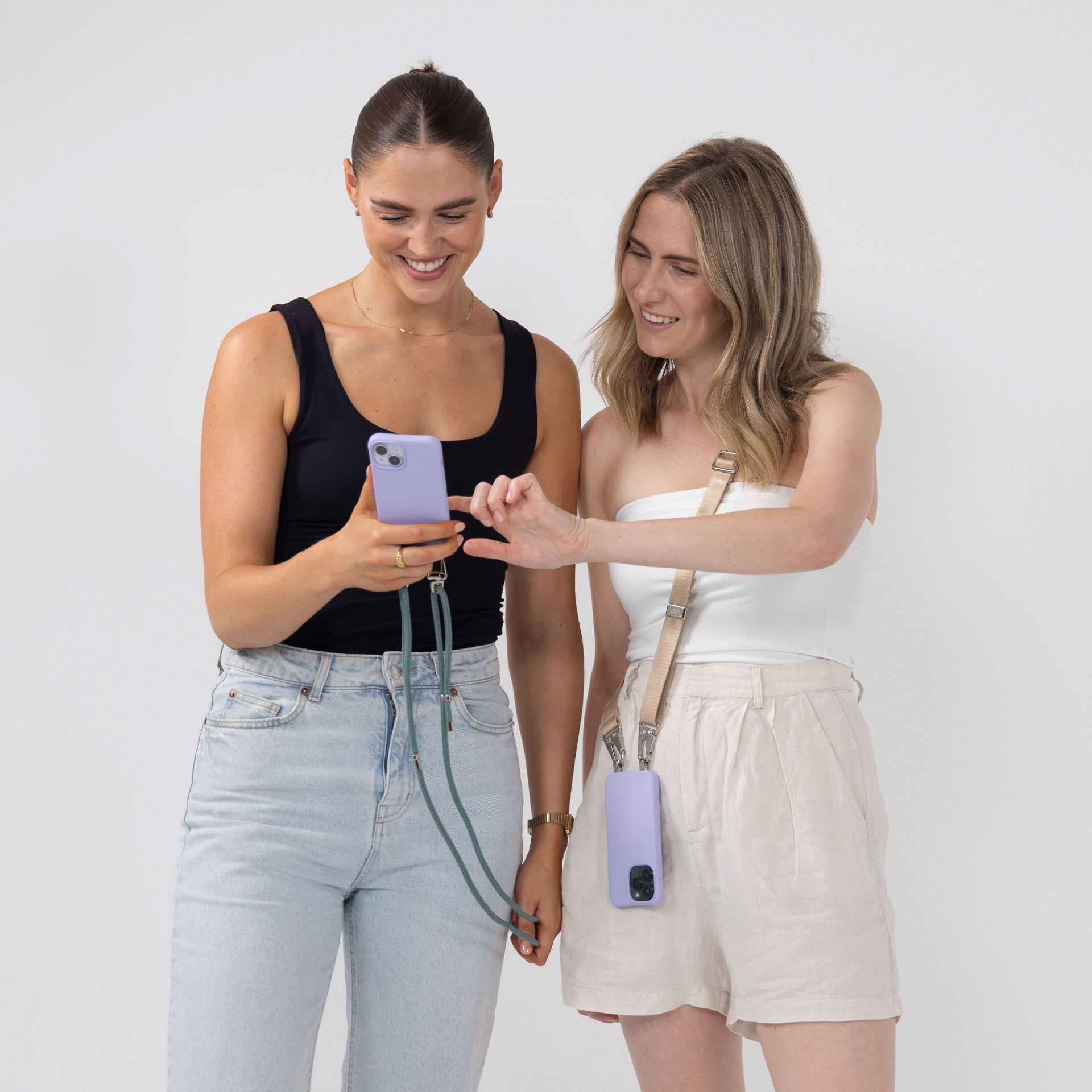 Lilac crossbody phone cases with seafoam and latter phone strap worn over shoulder and being held 