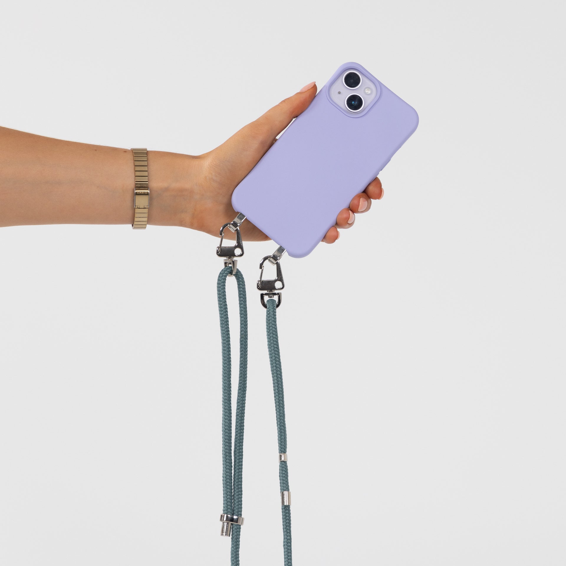 Lilac Loop crossbody phone case with seafoam cord attached being held in hand with rear of phone view