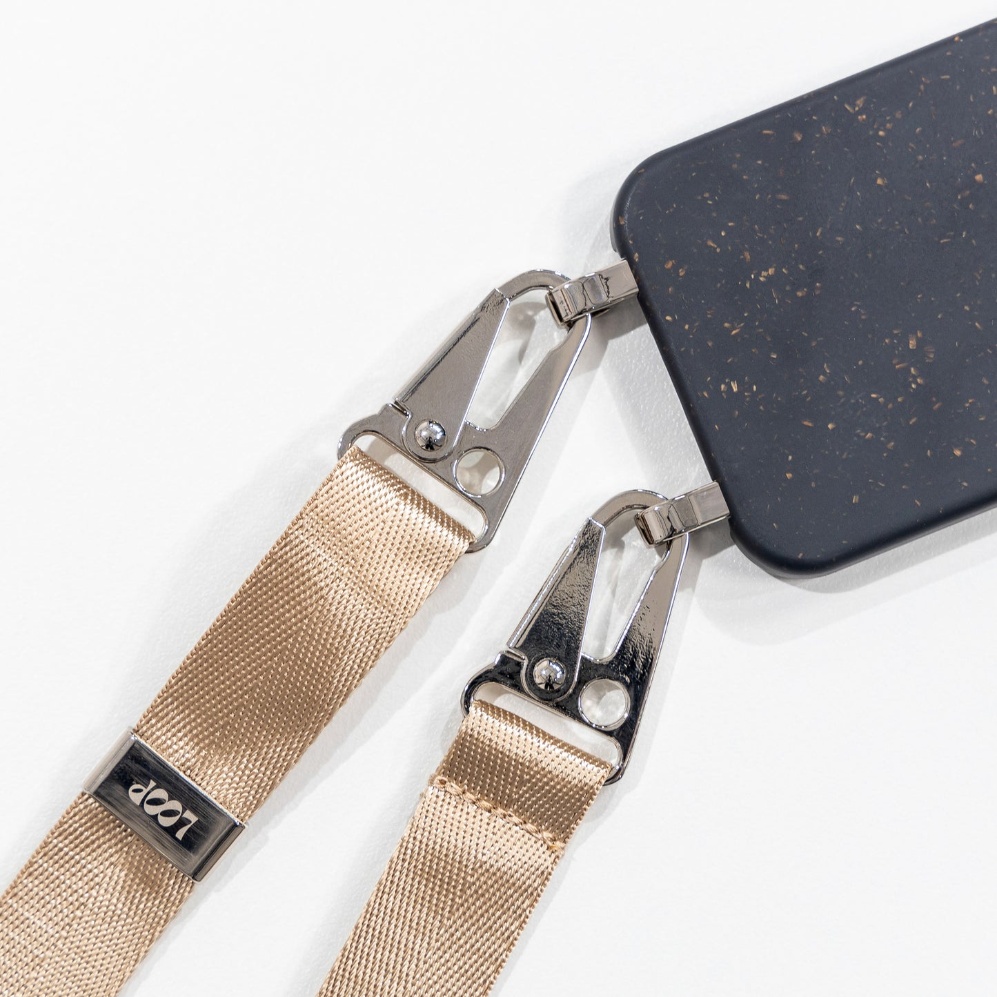 Speckled Ink crossbody phone case with latte phone strap attached laying flat face down