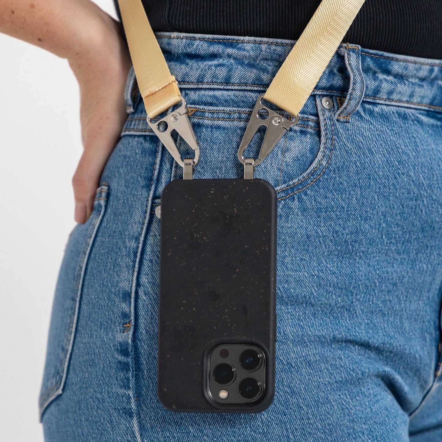 Speckled ink crossbody phone case with butter phone strap attached close up hanging over pocket