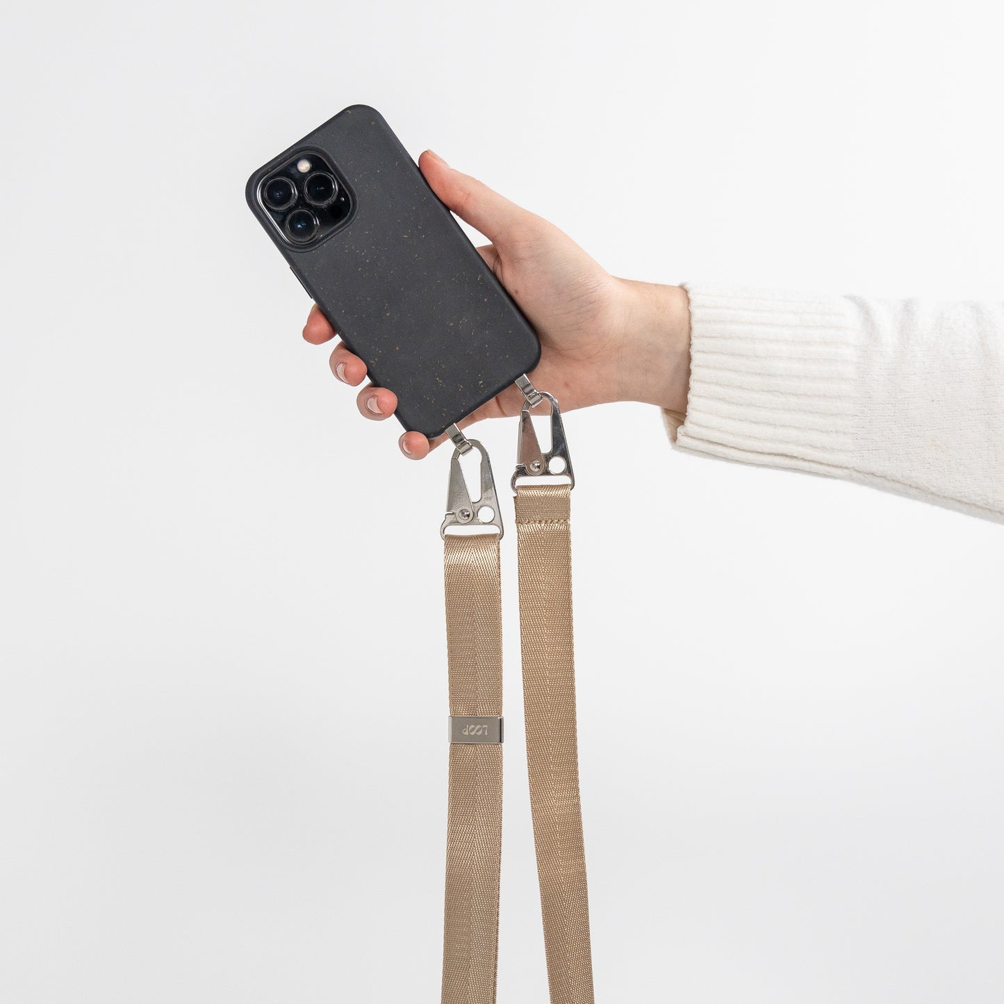 Ink crossbody phone case with latte phone strap attached being held in hand out from body