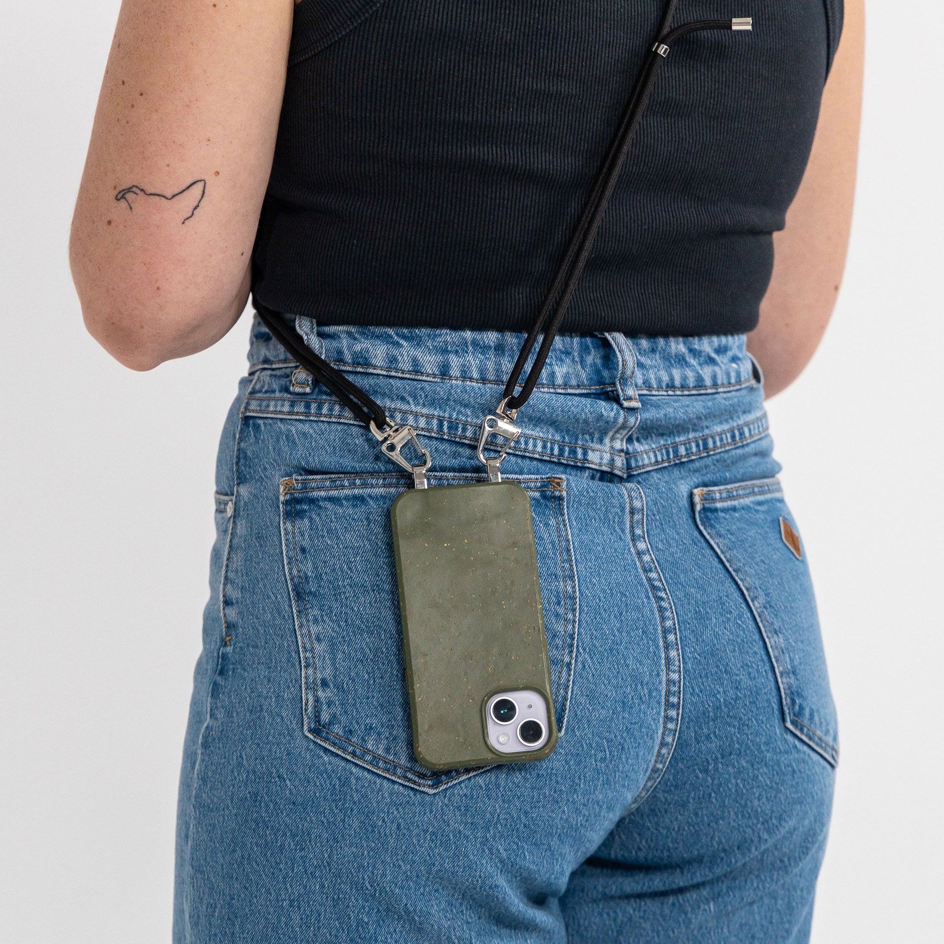 Pesto crossbody phone case with black cord being worn over shoulder