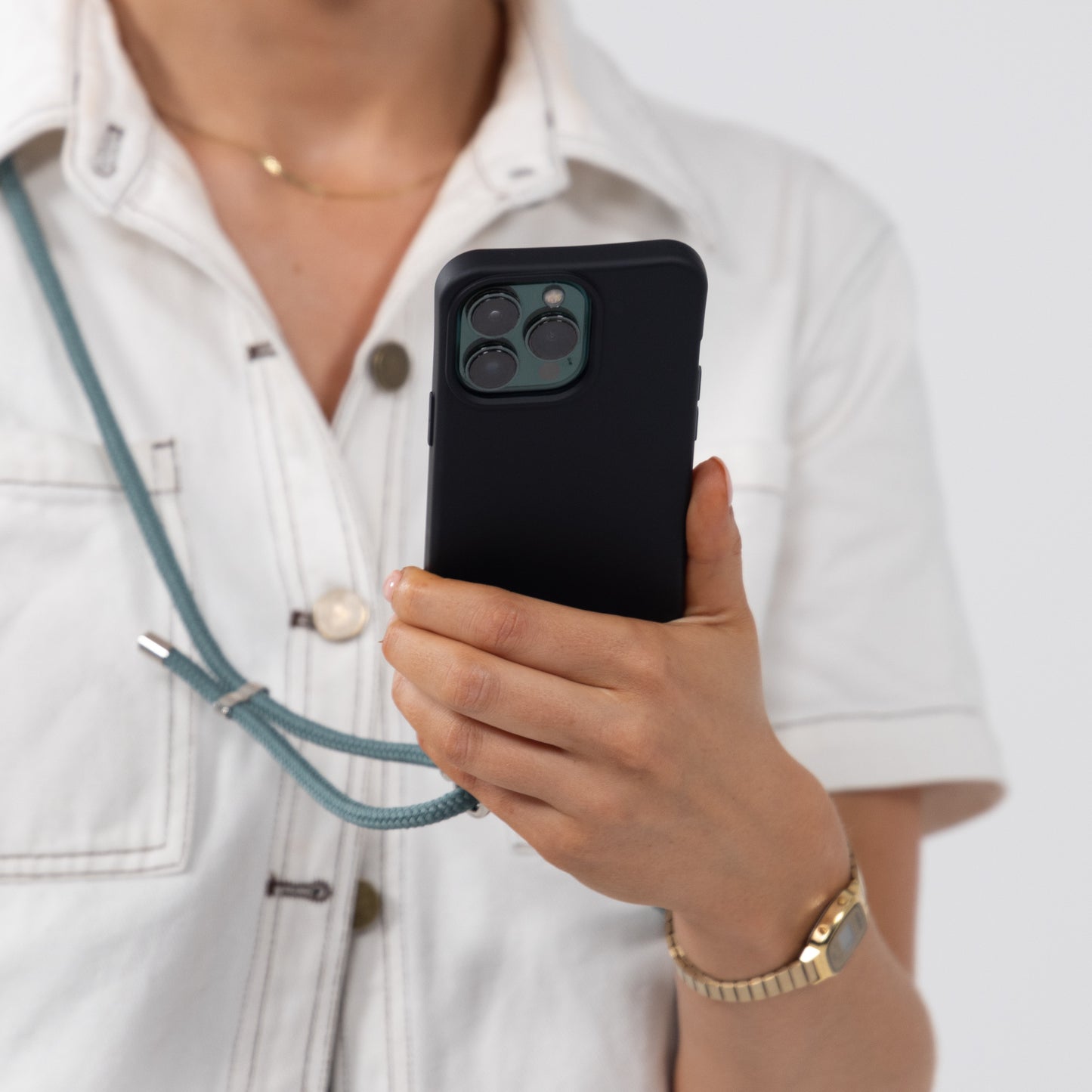 Ink crossbody phone case being held with seafoam crossbody cord over shoulder