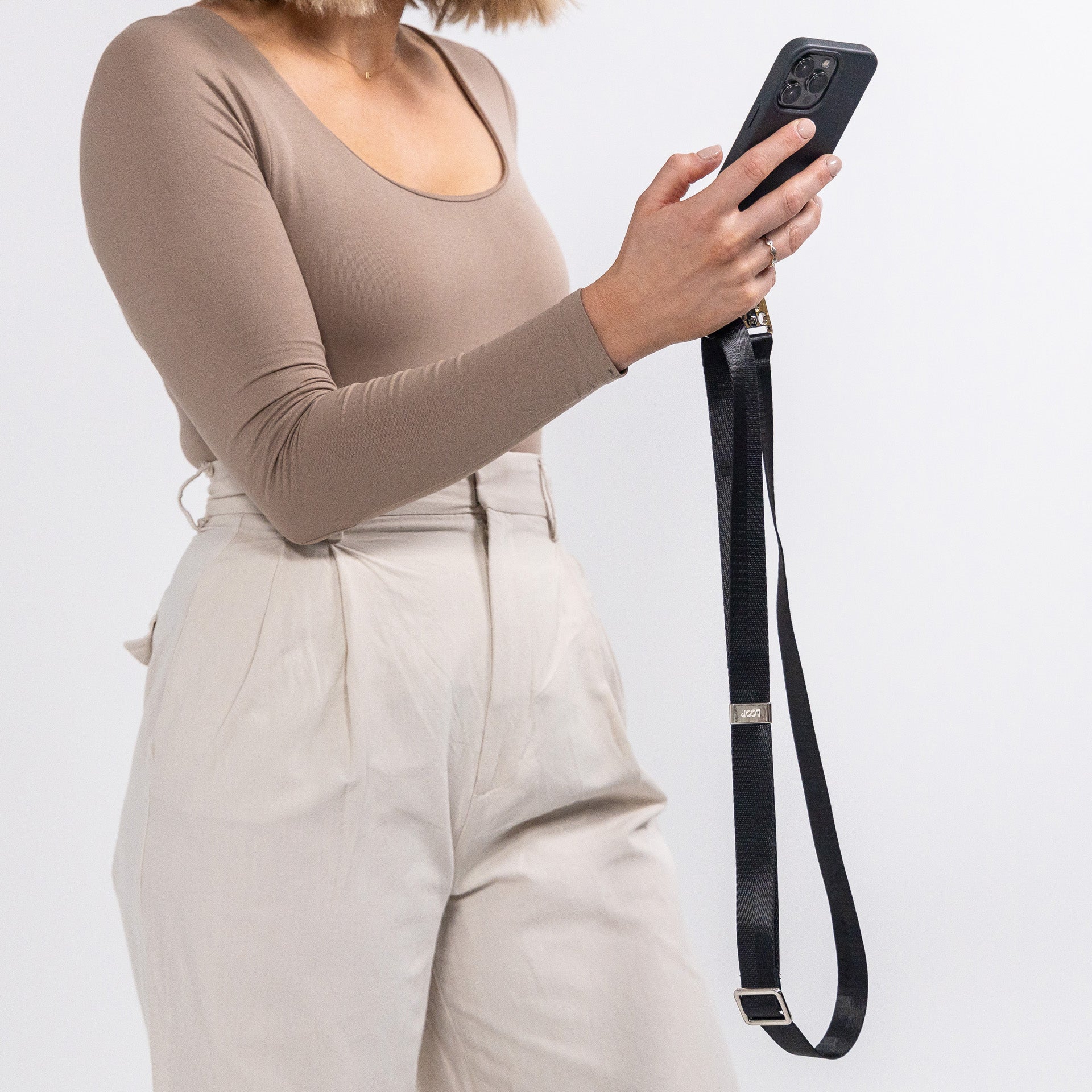 Loop ink crossbody phone case with black strap being held 
