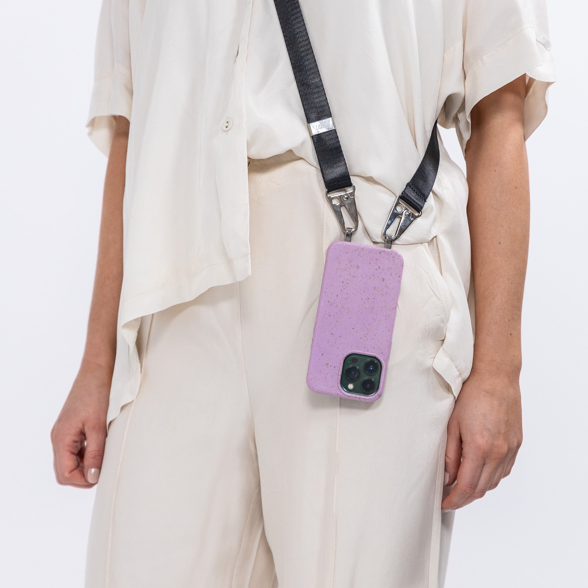 Crossbody phone case with black strap being worn over shoiulder