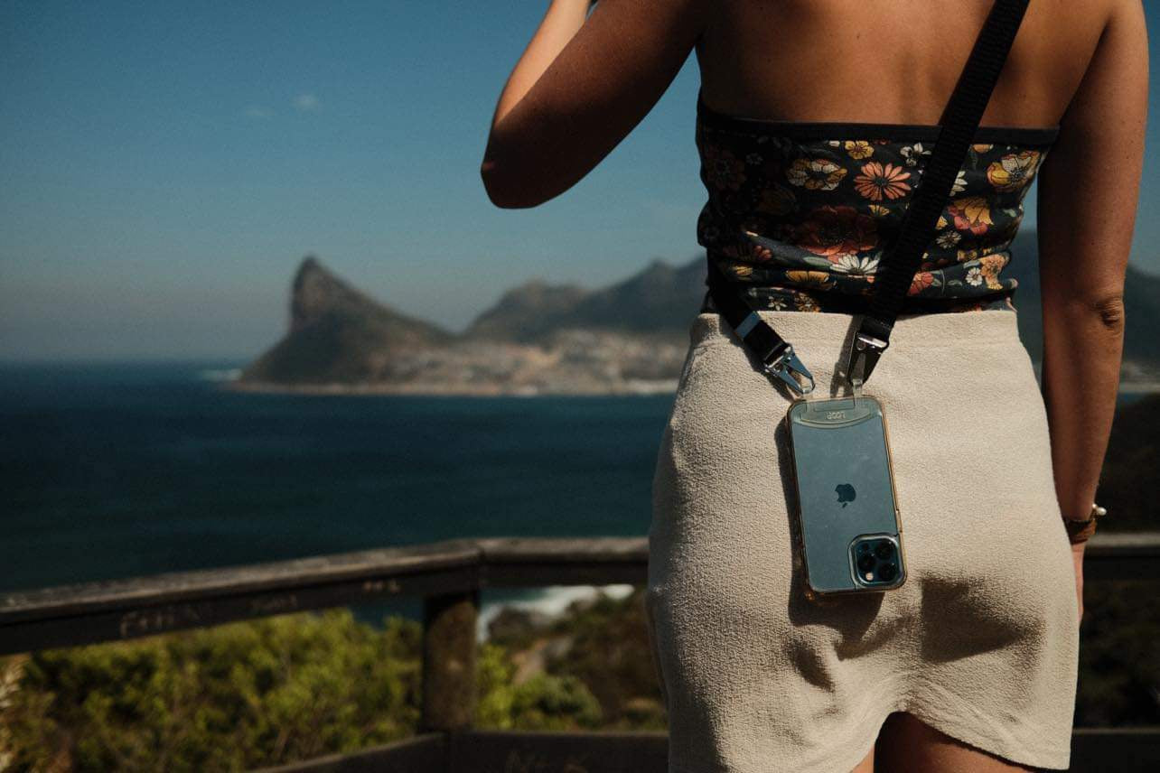 Female traveller wearing clear crossbody phone case with ink crossbody strap. overlooking cape town coast